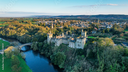 Aerial view of majestic Lismore Castle in County Waterford, Ireland, bathed in the golden glow of the setting sun on the first day of spring, showcasing its timeless beauty and historic charm