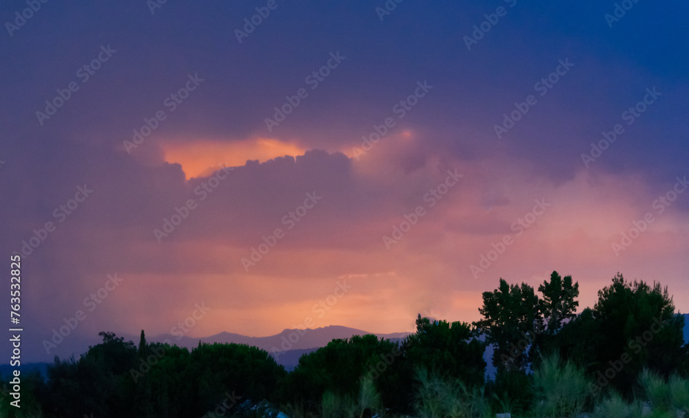 Twilight sky with vivid orange and purple clouds over mountain silhouette