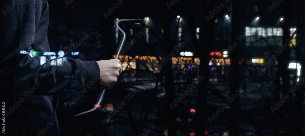 A burglar with a crowbar is preparing to break into a store. - obrazy, fototapety, plakaty 
