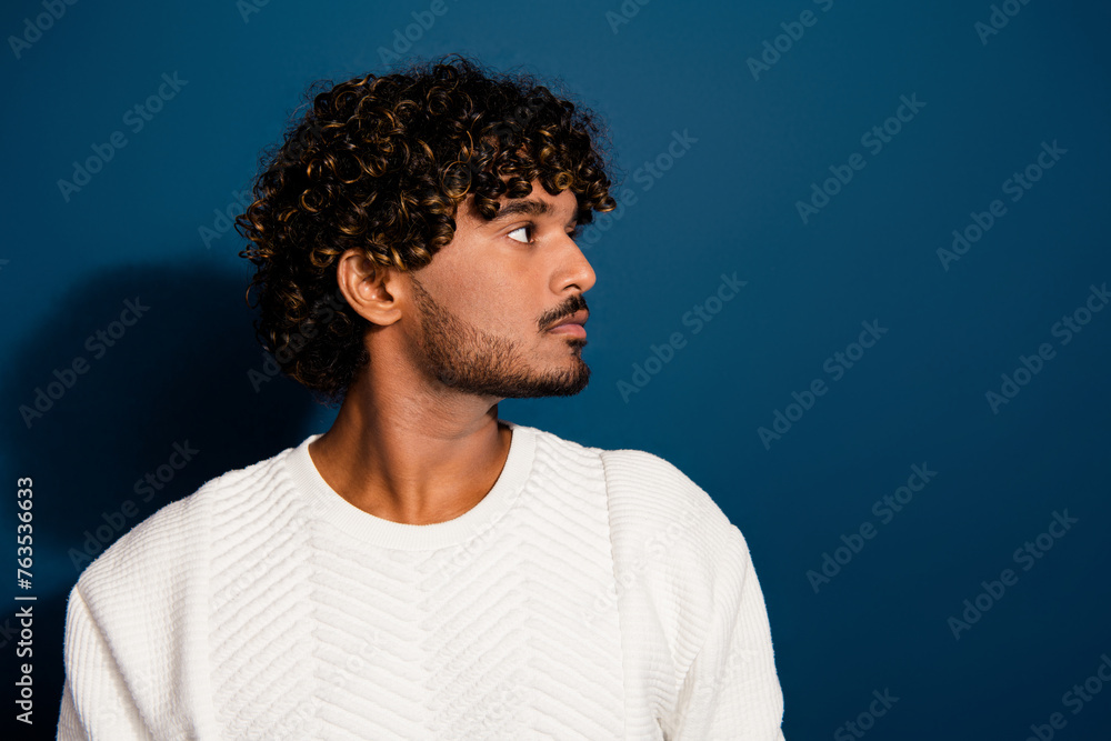 Obraz premium Side profile photo of latin guy in looking empty space demonstrate wavy hair with perfect stubble isolated on dark blue color background