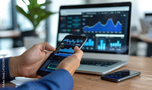 Businessman is holding a smartphone and checking stock and cryptocurrency markets