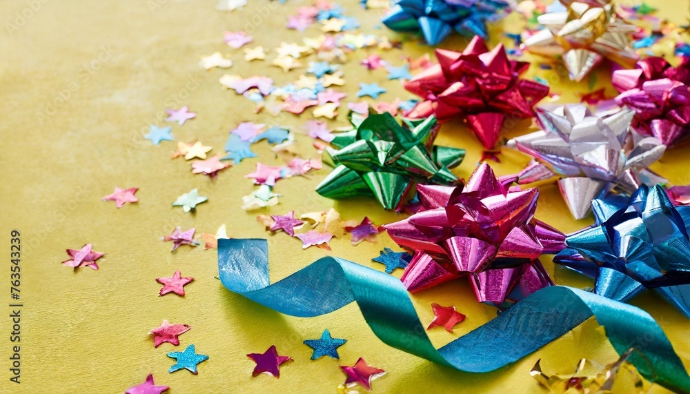 colorful ribbons with paper stars and confetti on yellow background