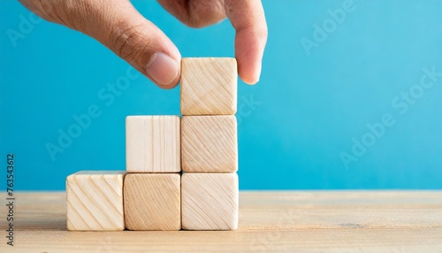 wooden cubes in the form of a ladder with a hand on a blue background