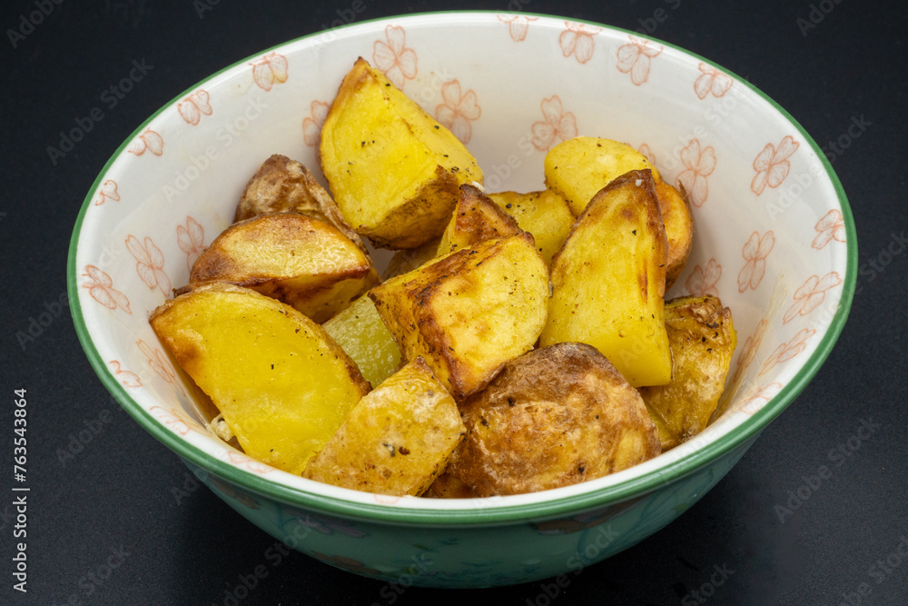 Bowl of crispy fried potatoes. Close-up with dark background Bowl of crispy fried potatoes. Close-up with dark background