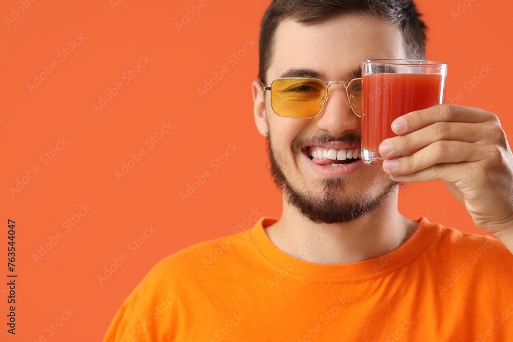 Young man with glass of juice on red background, closeup Young man with glass of juice on red background, closeup