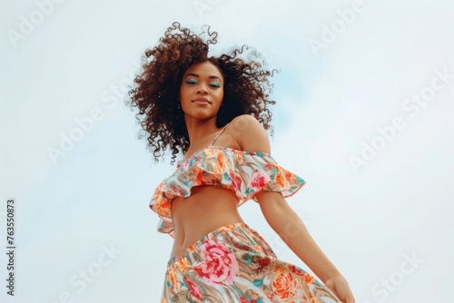 Beautiful African American woman with curly hair in a summer dress posing on a white background