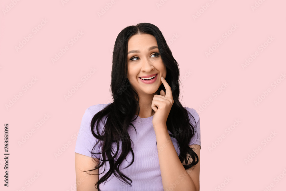 Fototapeta premium Beautiful young woman with dark wavy hair on pink background