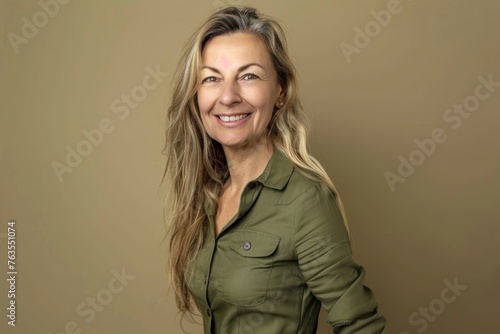 A portrait of an attractive smiling woman in her late forties with long blonde hair wearing green shirt dress photo