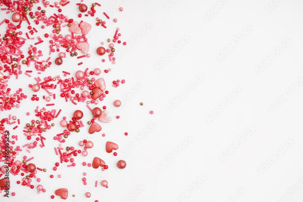 Sweet pink sprinkles scattered on white background