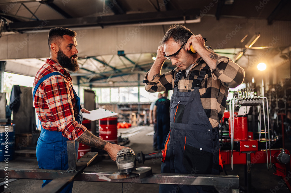 © Zamrznuti tonovi - Men in plaid shirts and work overalls working together in a workshop. © Zamrznuti tonovi - Men in plaid shirts and work overalls working together in a workshop.