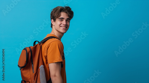 Garoto jovem com uma mochila nas costas isolada no fundo azul