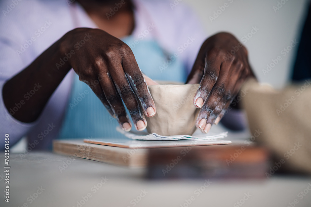 Cropped picture of interracial attendee's hands making pottery on class