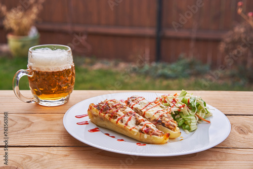 Stuffed white peppers served on white plate with vegetable salad and small mug of pilsner beer served outside on the wooden table of garden restaurant like light and healthy lunch in Czech republic.