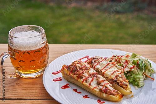 Stuffed yellow pepper with minced pork meat, rice and cheese with vegetable salad and served outside in garden restaurant with pint of czech pilsner beer. Delicious dish from cuisine of Czech Republic