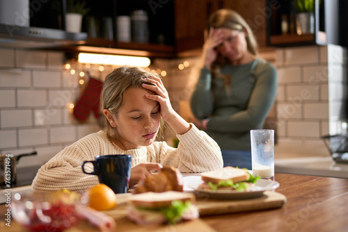 Фотография The daughter, looking weary, attempts to focus on her studies, while her stressed mother, holding her head, tries to convey the importance of perseverance