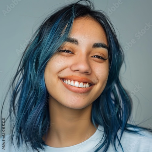 Embrace the cerulean beauty in this skincare portrait of a joyful 20-year-old Latina model showcasing blue hair. Against a soft backdrop, with a luminous filter effect and ambient studio lighting