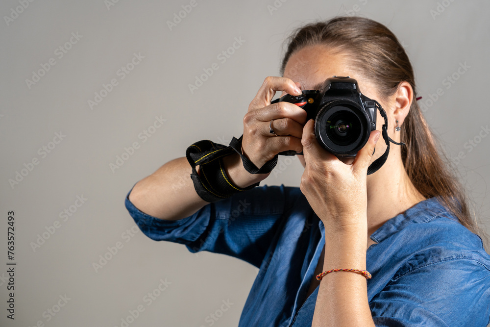 Mujer fotógrafa tomando una fotografía apuntando su cámara al espectador Mujer fotógrafa tomando una fotografía apuntando su cámara al espectador