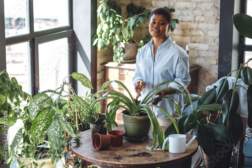 Concept of mental health, hobbies, do favourite things on leisure time. African American woman doing home gardening, repotting plants, taking care about flowers. Domestic life, interior design