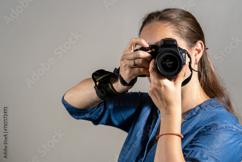 Mujer fotógrafa tomando una fotografía apuntando su cámara al espectador photo