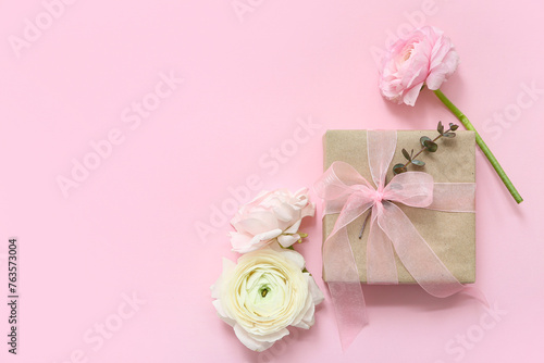 Wrapped gift box with flowers on pink background