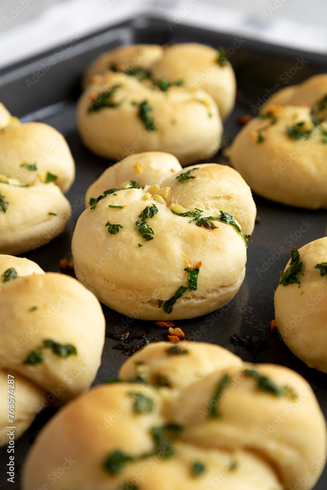 Homemade Garlic Knots with Parsley on a Baking Tray, side view.