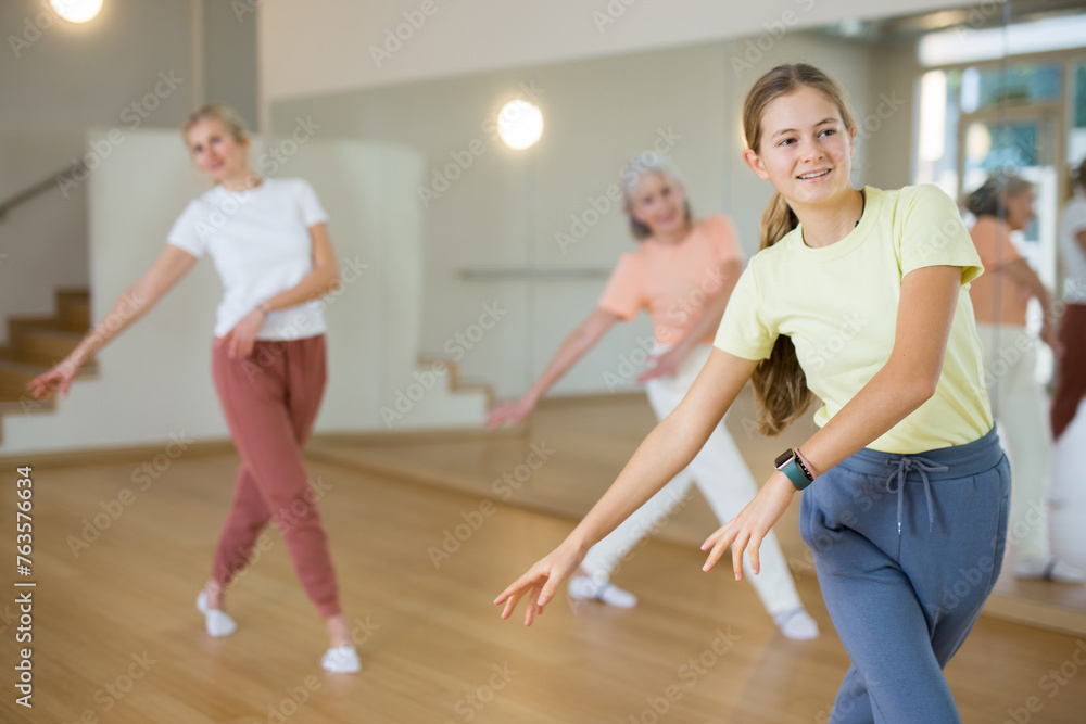 Caucasian girl learning to dance during group training in studio.