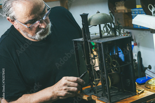 Foto Clockmaker making adjustments to the gears of a large wall clock.