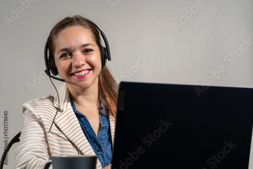 Mujer asistente en una tele llamada, sonriente y mirando a cámara. Concepto de mesa de ayuda y asistencia virtual photo