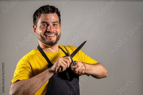 Photos Carnicero afilando su cuchillo mientras sonríe a cámara