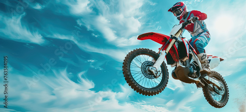 A motocross rider catches air against a backdrop of a vivid blue sky