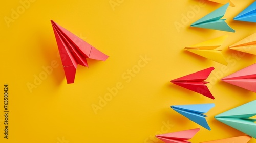 The concept of opinion leadership with a red paper plane leading a group of colorful ones, influencing the crowd on a yellow background photo