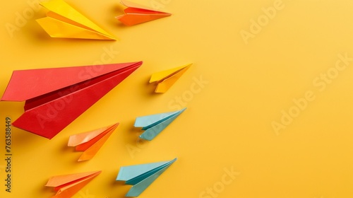The concept of opinion leadership with a red paper plane leading a group of colorful ones, influencing the crowd on a yellow background photo