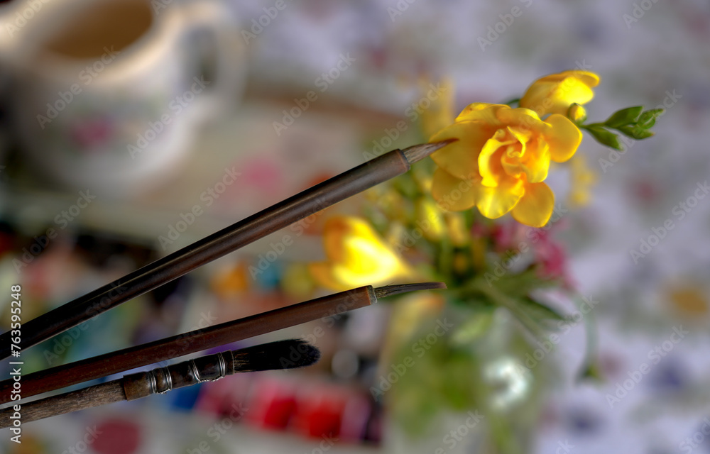 Artistic brushes close up on blurred background of watercolor pallet and flowers Artistic brushes close up on blurred background of watercolor pallet and flowers