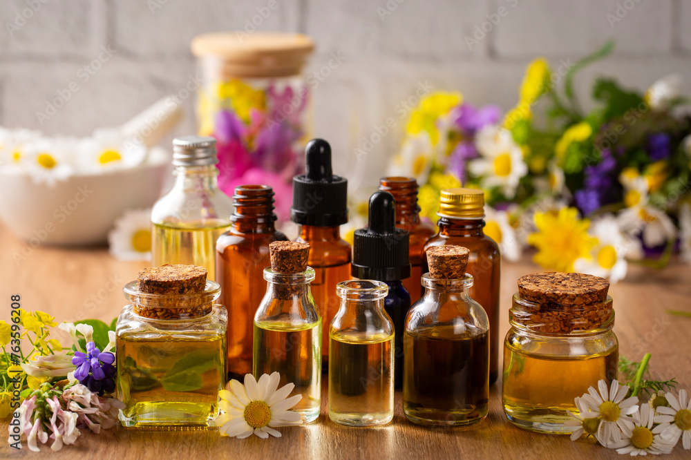 Concept of alternative herbal medicine. Bottles of tincture or potion, organic essential oils, dry healthy herbs, floral extracts on wooden table. Pure natural ingredients for cosmetic production