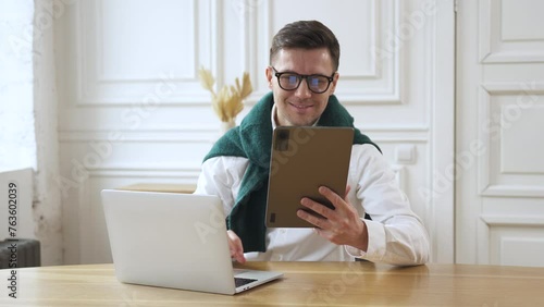 A person uses a tablet and computer in an office environment. A freelance worker is a creative individual who works remotely with clients.
 photo