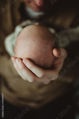 fathers hand holding newborn baby's head