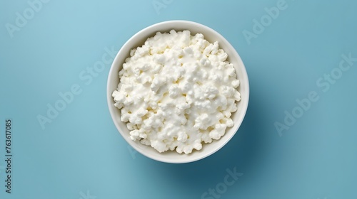 Cottage cheese in glass bowl isolated on blue background, top view