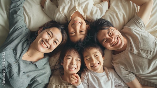 Happy Asian family lying on bed in bedroom with happy and smile, top view.