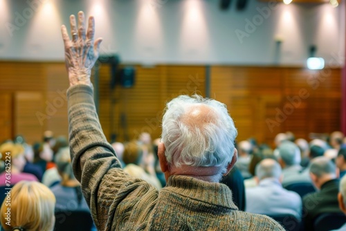 Elderly gentleman with raised hand actively participating in a conference or seminar atmosphere
