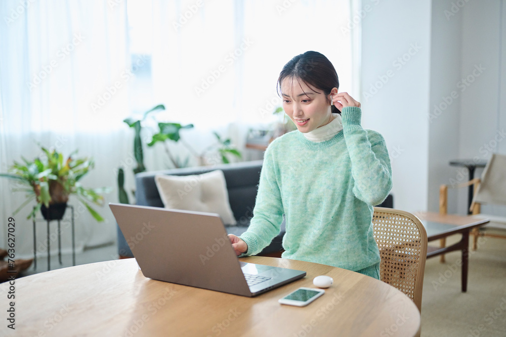 リビングでオンラインミーティングをする20代女性 リビングでオンラインミーティングをする20代女性