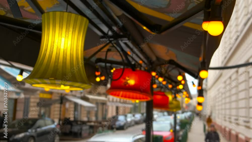 Burning cafe lamps in day street. A view of red and yellow burning cafe lamps in the road against city architecture. Burning cafe lamps in day street. A view of red and yellow burning cafe lamps in the road against city architecture.