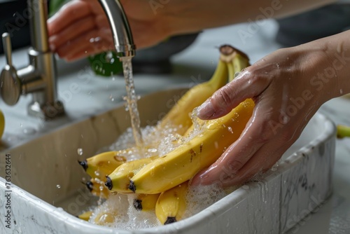 A person washes a bunch of bananas in a kitchen sink, preparing them for consumption.