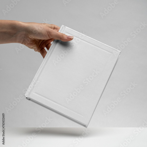 Female hands holding a blank notebook. Hardcover book. Matte white. Blank book mockup. Textured paper. (real photo) 3D render.  (ID: 763632669)