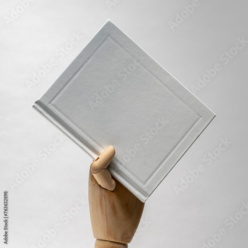 Wooden hand holding. Hardcover book. Matte white. Blank book mockup. Textured paper. (real photo) 3D render  (ID: 763632898)