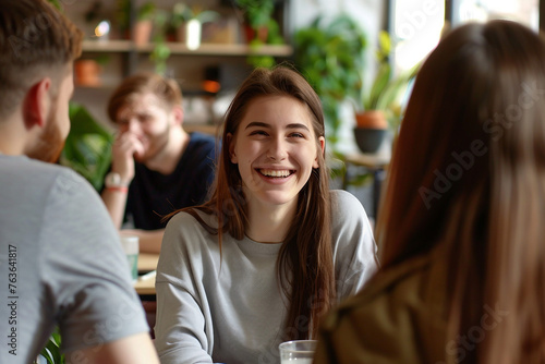 Smiling happy young woman talking with male colleagues at shared workplace worker laughing at funny joke reading funny news excited business success employees having break pause