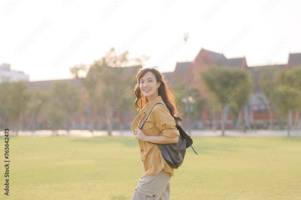 Traveler asian woman in her 30s stands bathed in the golden glow of sunset, embracing the freedom of exploration. on summer holiday weekend vacation trip in Bangkok, Thailand