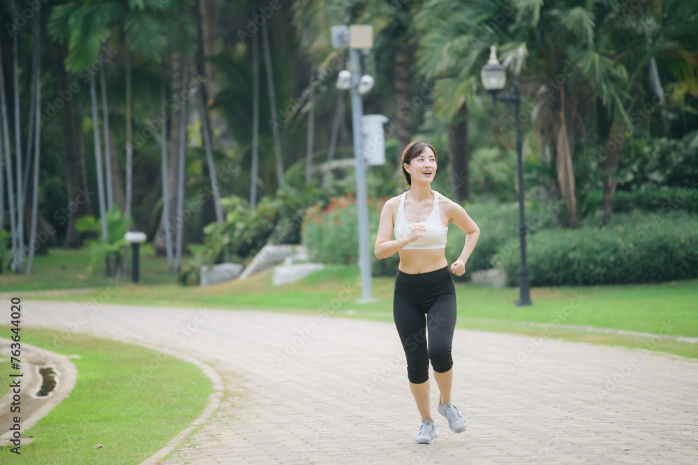 asian woman jogger running in green nature public park.