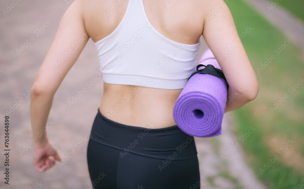 back of fitness yoga woman walking in the park with yoga mat back of fitness yoga woman walking in the park with yoga mat