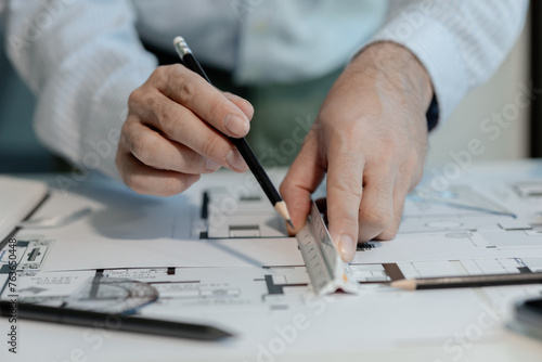 An engineer is working in his office and using various equipment to help with his work. An architect is working in a transparent office filled with documents and a nice atmosphere.