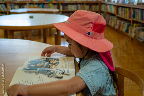 Little girl reading a picture book at the library